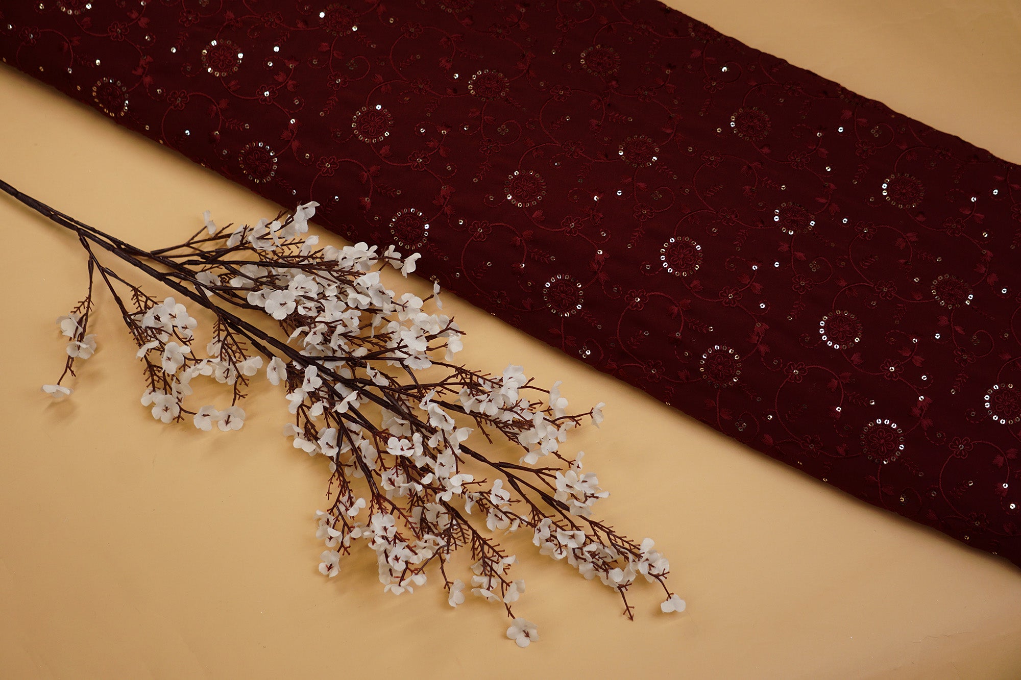 Thread work with golden sequins creating floral overall pattern on maroon georgette fabric - Paras Gallery Fabrics