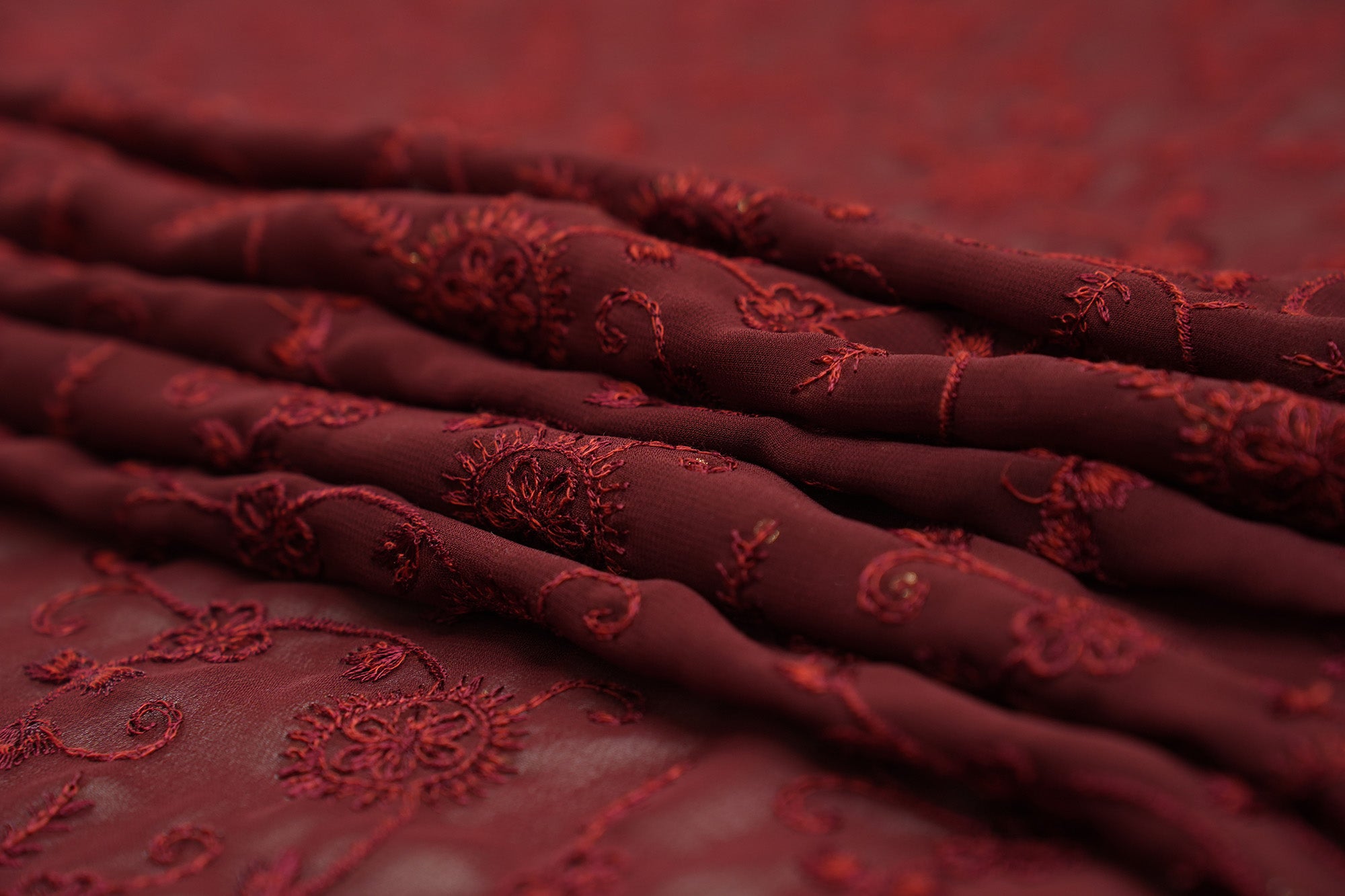 Thread work with golden sequins creating floral overall pattern on maroon georgette fabric