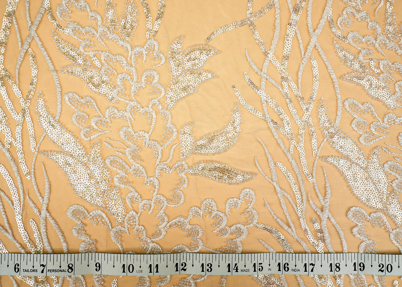Close-up of a luxurious fabric featuring an intricate gold and silver floral pattern