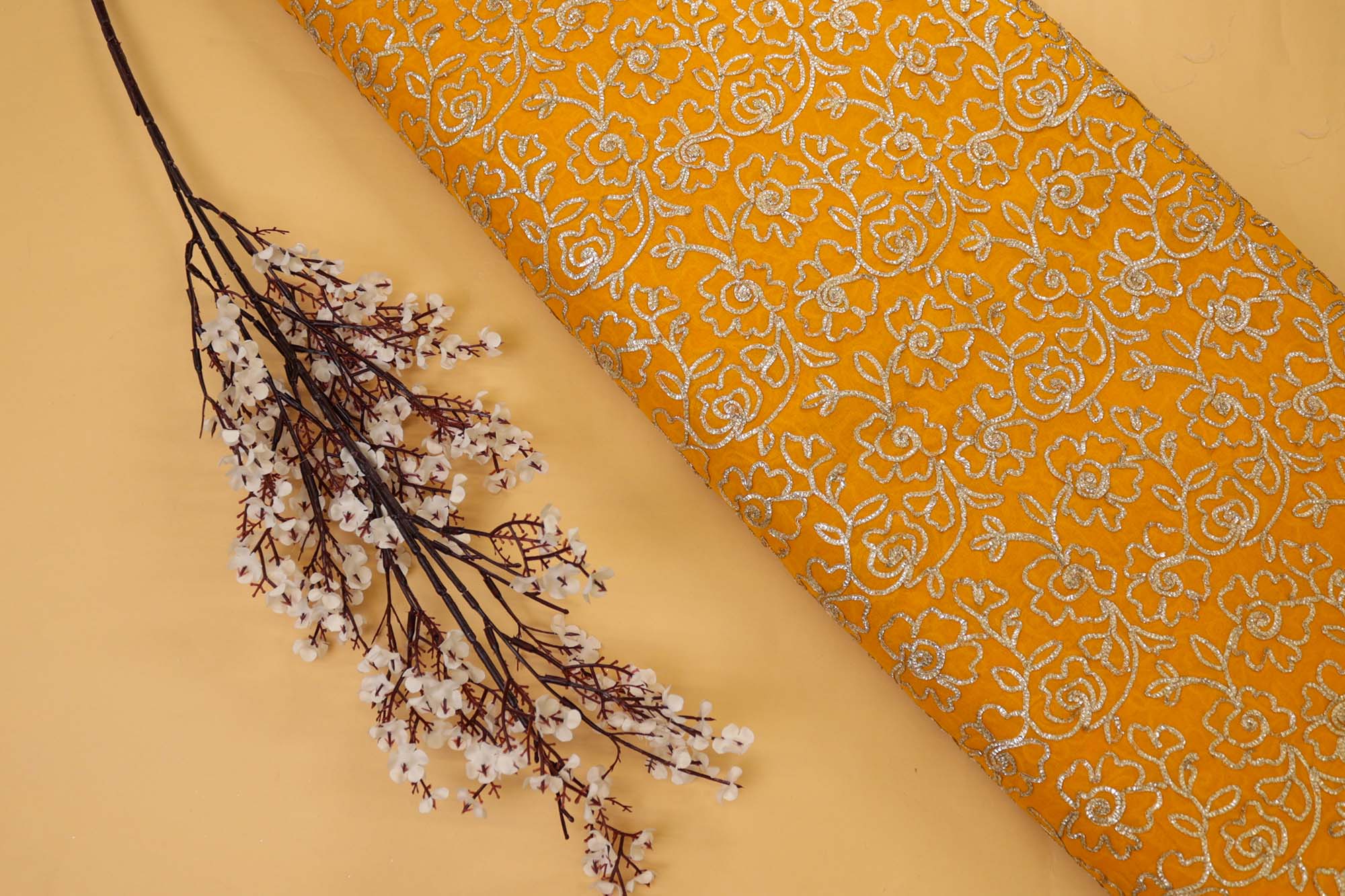 Mustard yellow georgette fabric with gotta patti work creating floral allover pattern