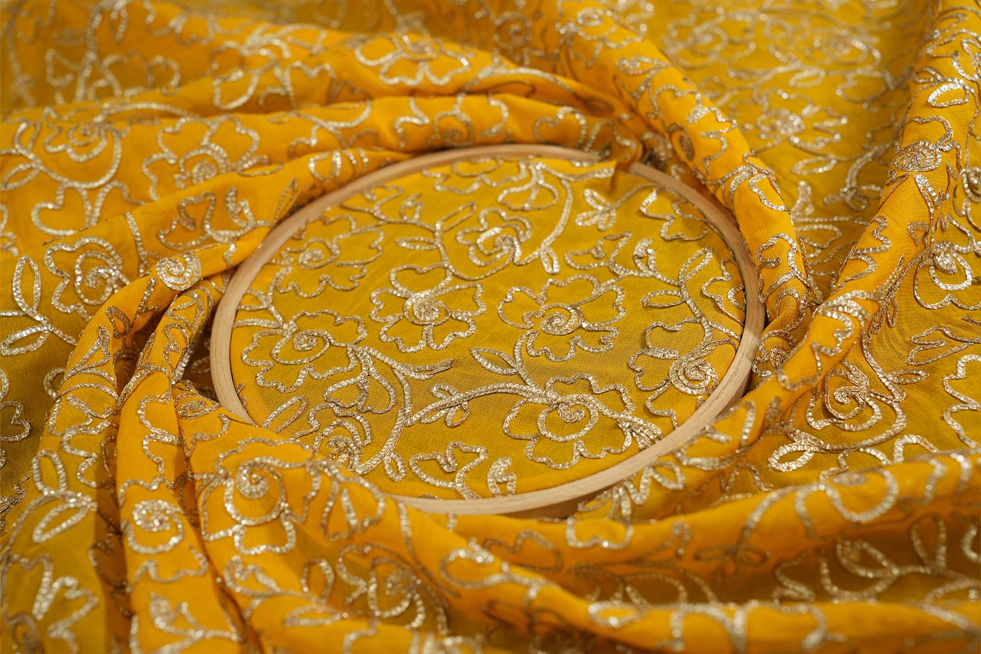 Mustard yellow georgette fabric with gotta patti work creating floral allover pattern