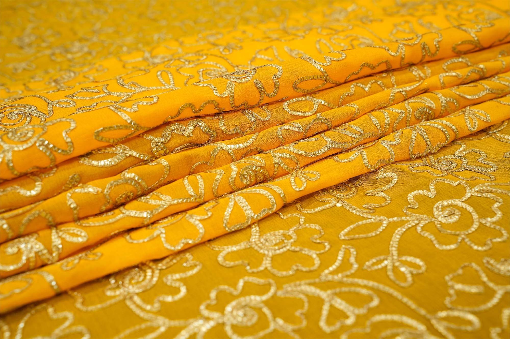 Mustard yellow georgette fabric with gotta patti work creating floral allover pattern