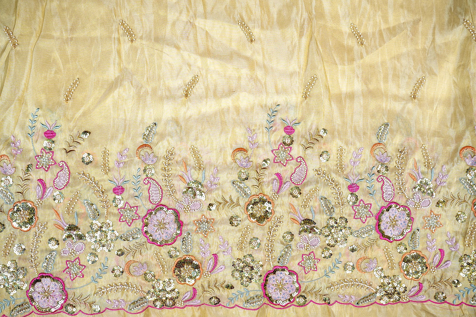 Close-up of yellow silk fabric adorned with intricate floral and leaf patterns