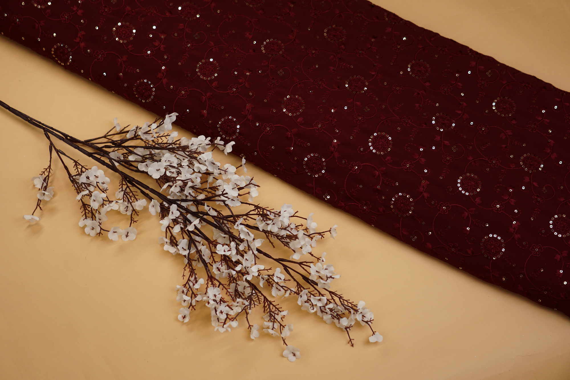 Thread work with golden sequins creating floral overall pattern on maroon georgette fabric