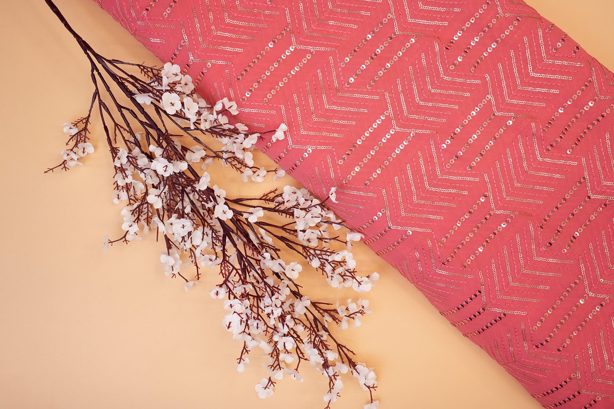 Thread work with golden sequins creating abstract pattern on peach georgette fabric