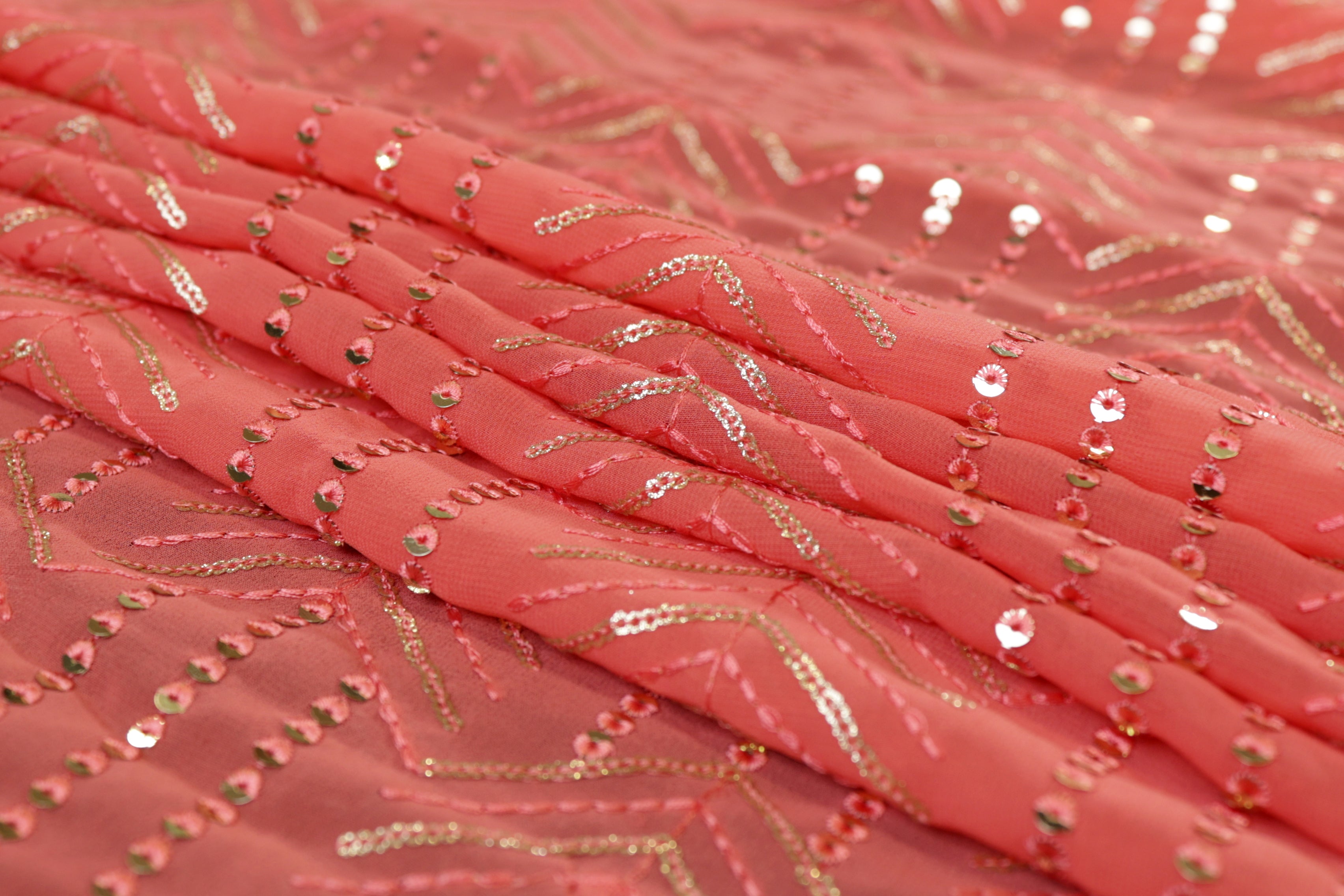 Thread work with golden sequins creating abstract pattern on peach georgette fabric