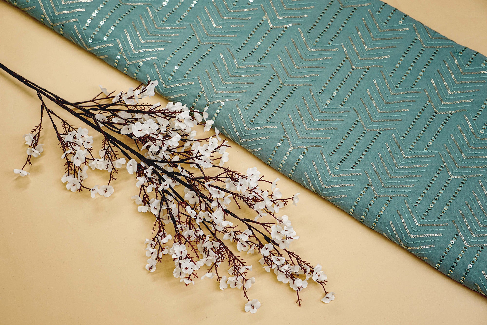 Thread work with golden sequins creating abstract pattern on teal georgette fabric