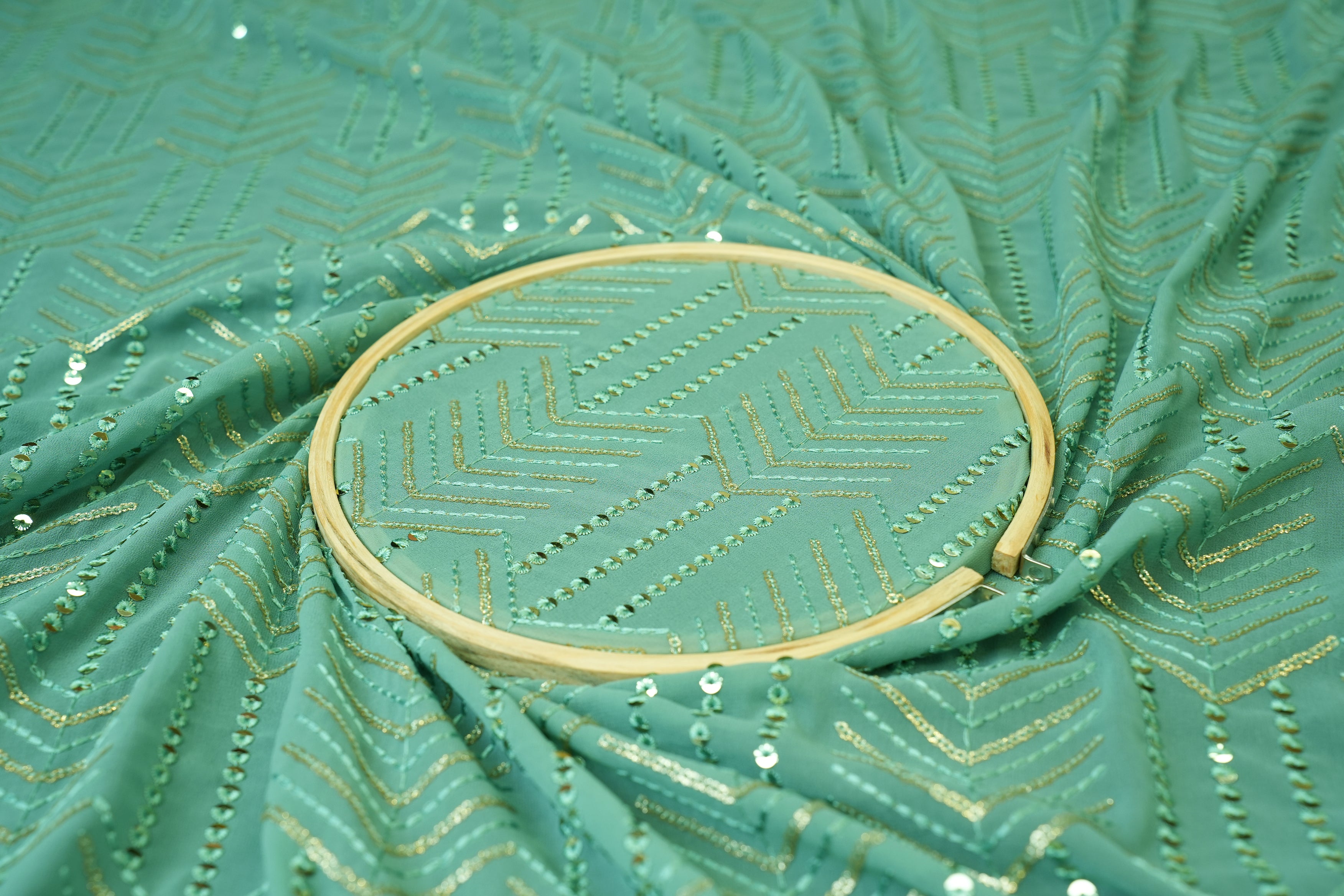 Thread work with golden sequins creating abstract pattern on teal georgette fabric