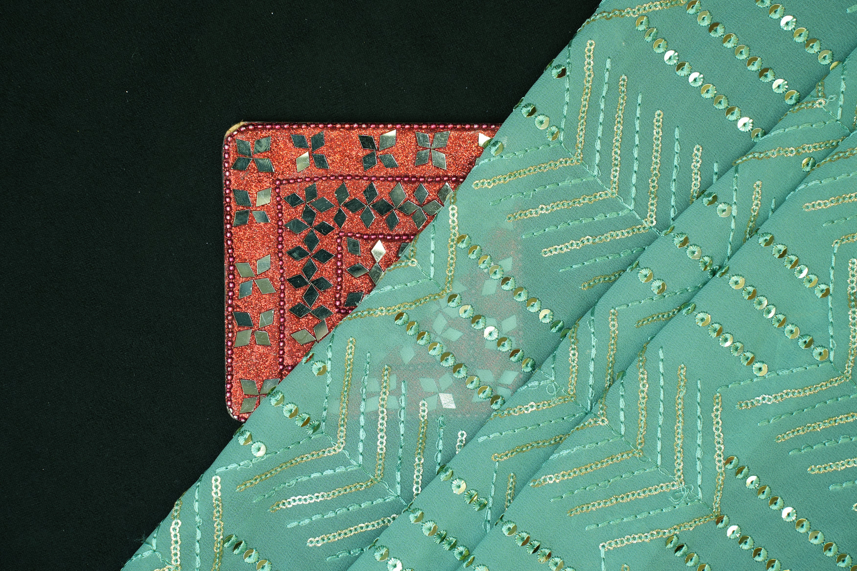 Thread work with golden sequins creating abstract pattern on teal georgette fabric