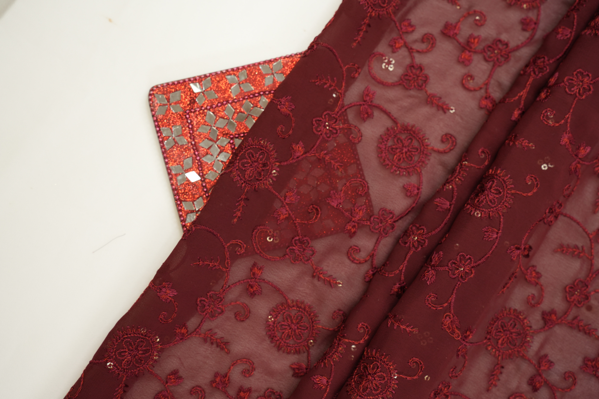 Thread work with golden sequins creating floral overall pattern on maroon georgette fabric