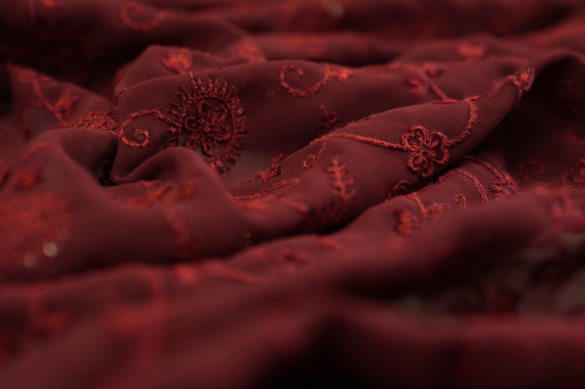 Thread work with golden sequins creating floral overall pattern on maroon georgette fabric