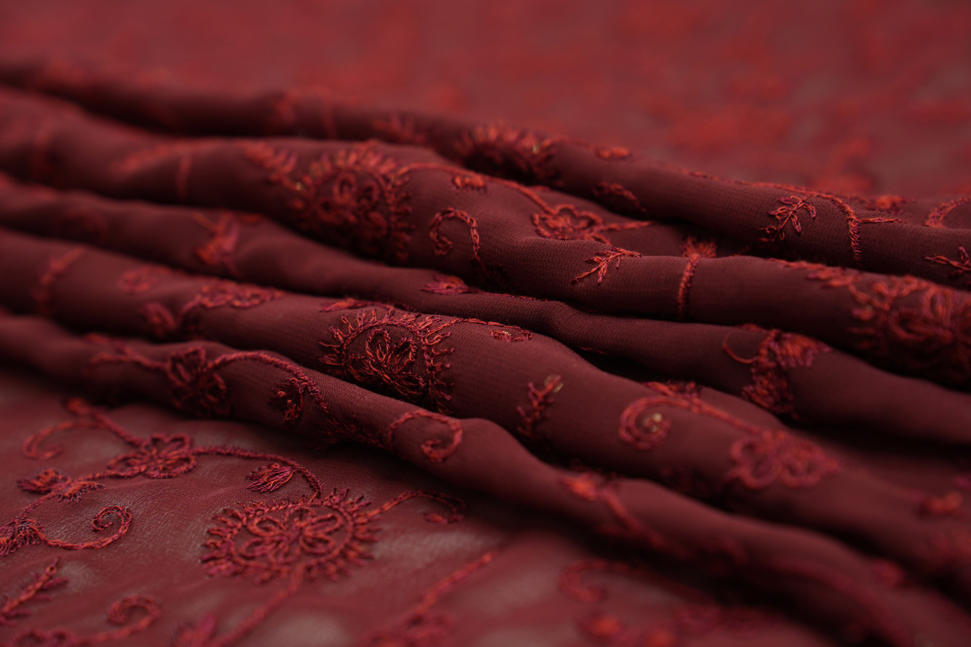 Thread work with golden sequins creating floral overall pattern on maroon georgette fabric