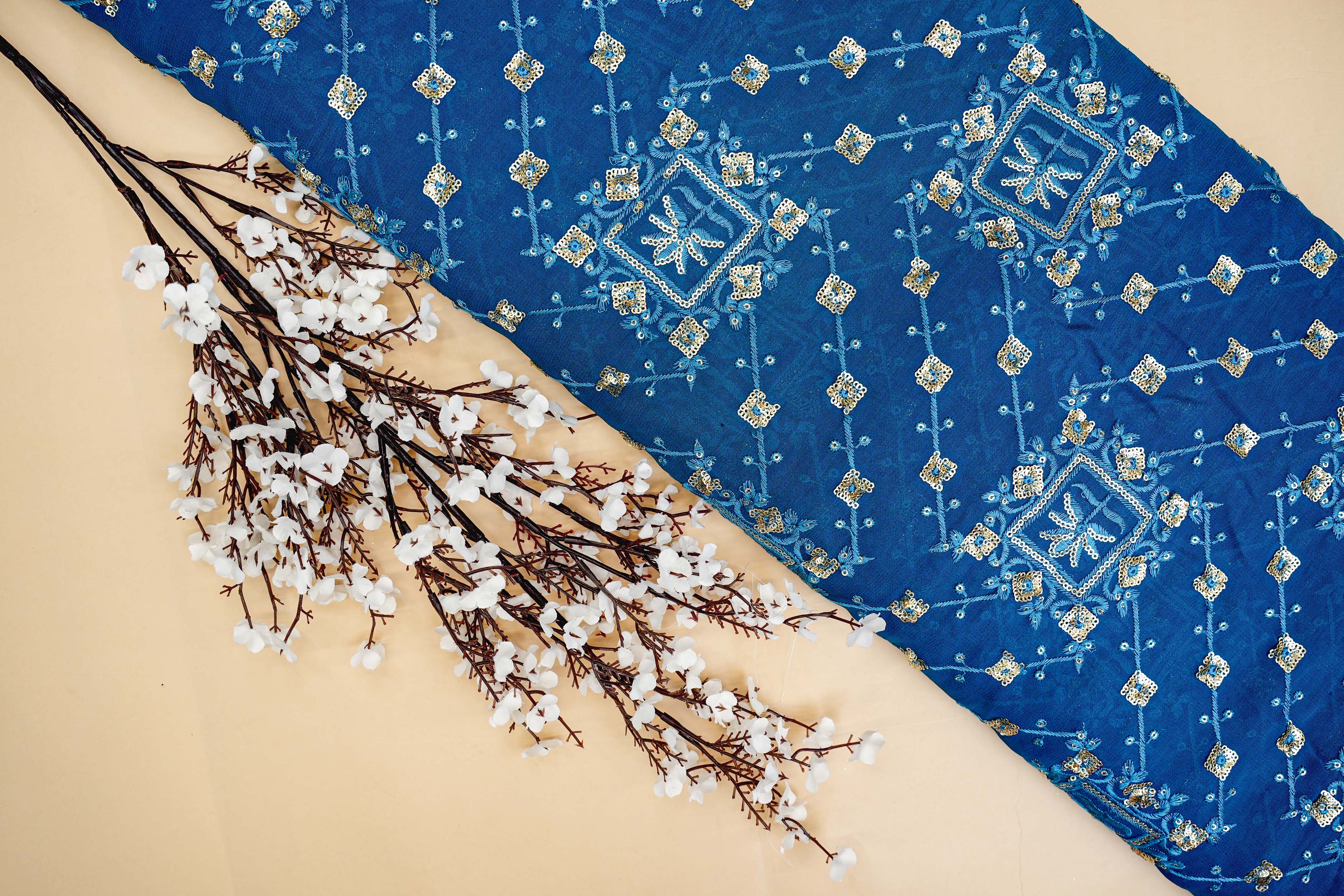 Blue georgette fabric with thread with golden sequins creating geometric allover pattern