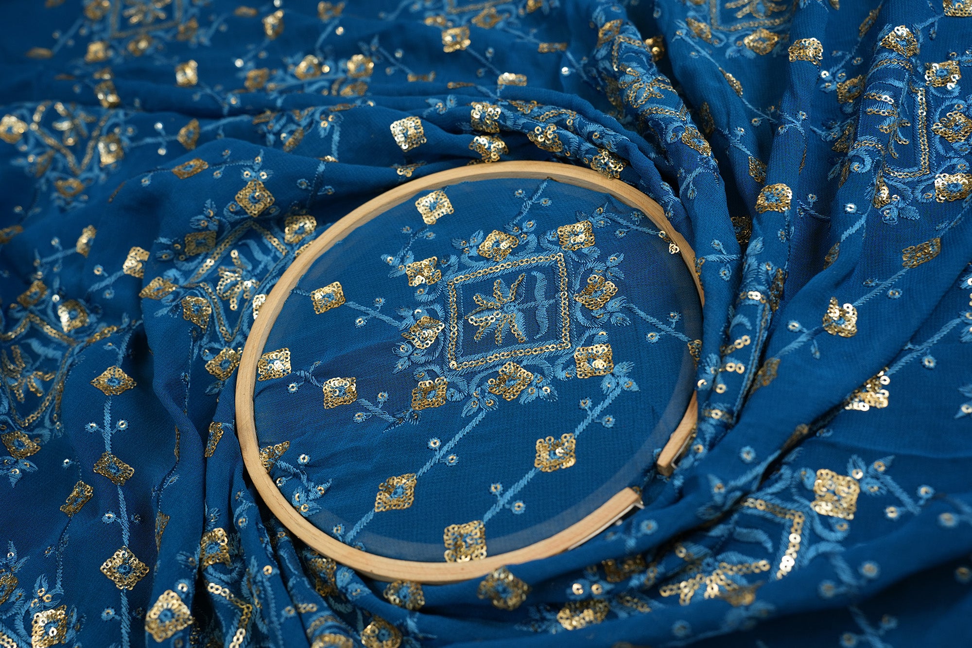 Blue georgette fabric with thread with golden sequins creating geometric allover pattern