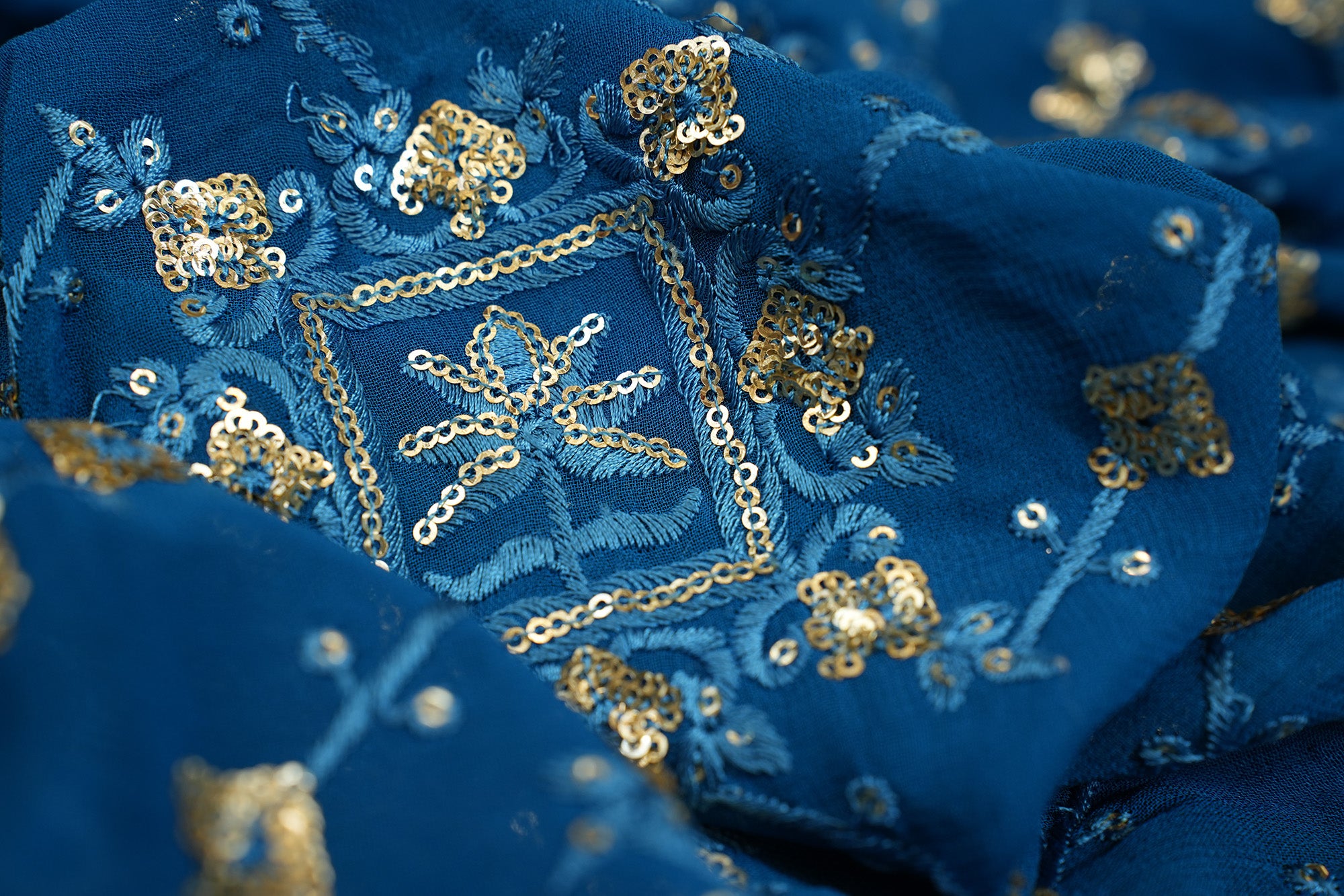 Blue georgette fabric with thread with golden sequins creating geometric allover pattern