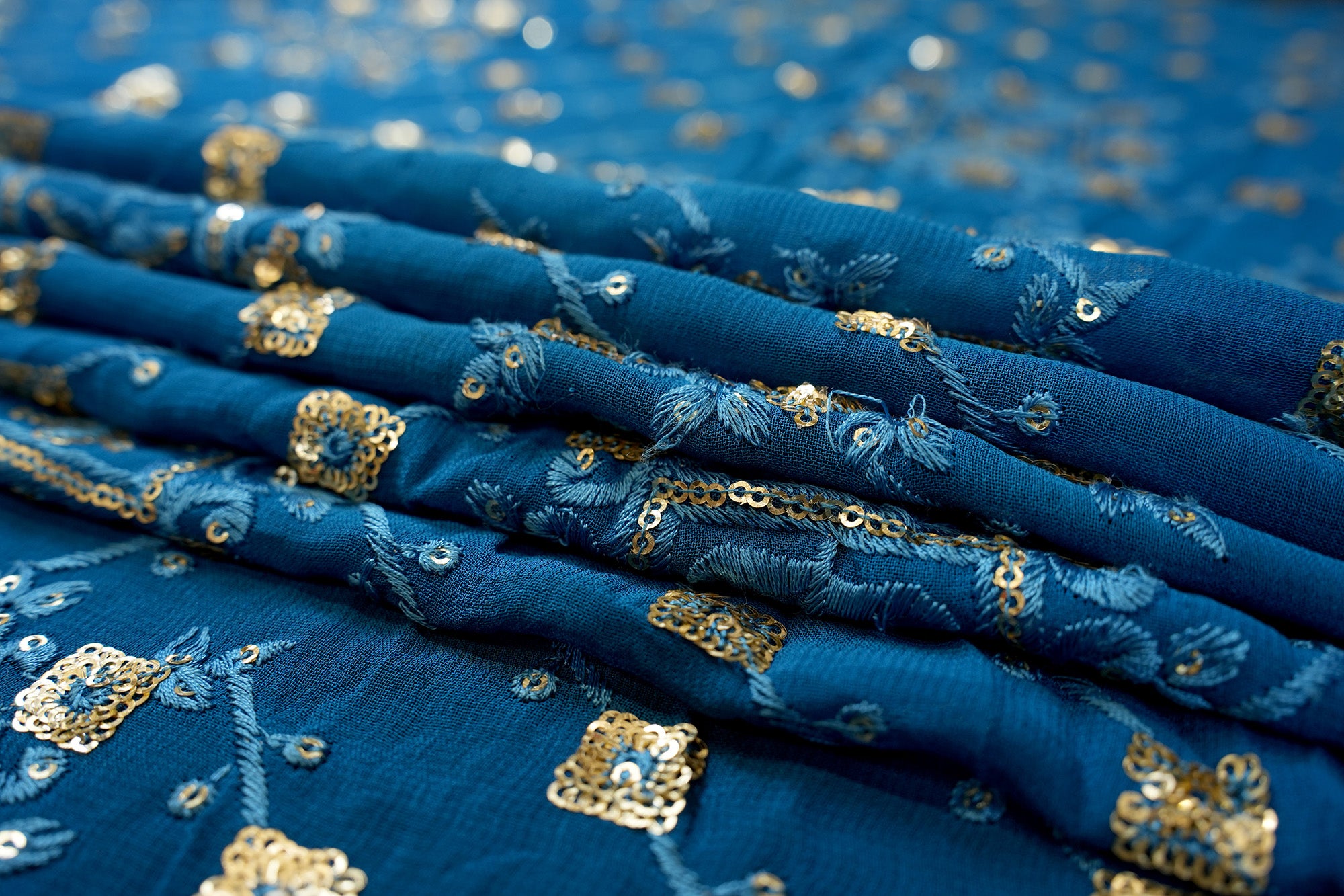 Blue georgette fabric with thread with golden sequins creating geometric allover pattern