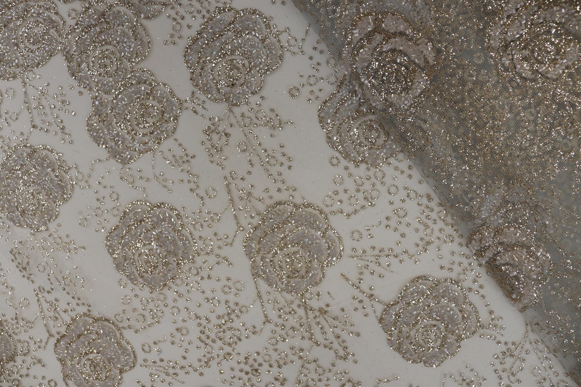 Light grey net with glitter and beads work allover creating floral pattern .