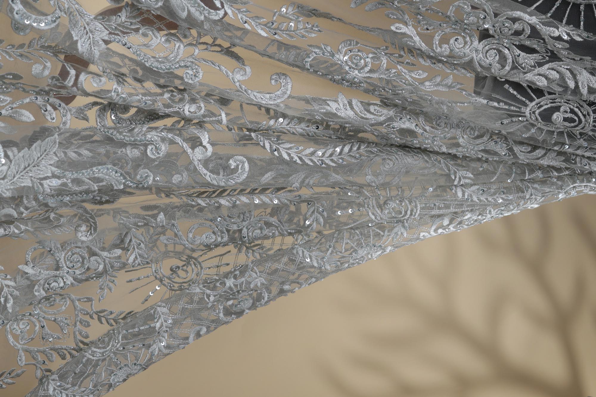 Grey net fabric with thread , sequins , pearls and bead work creating abstract pattern allover.